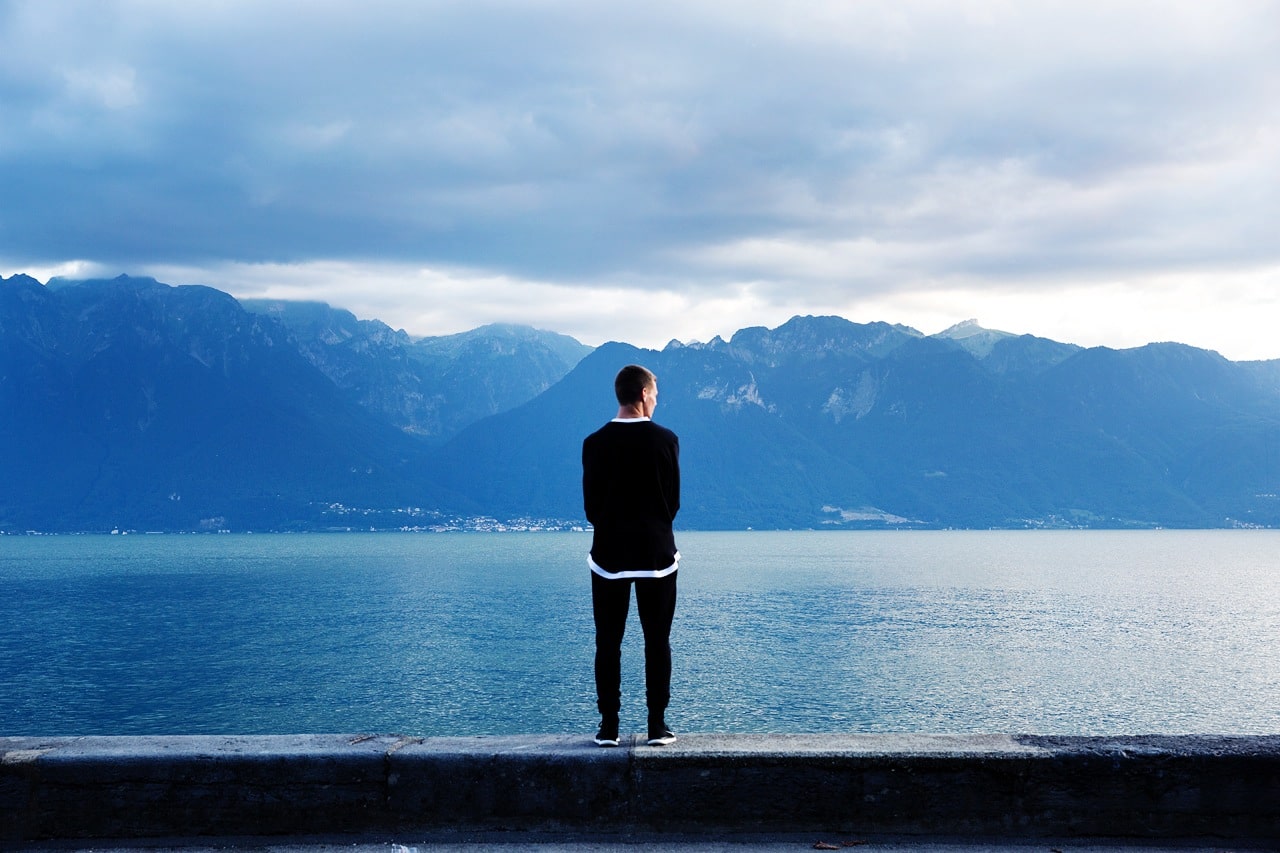 14 Oranges Man looking at Lake with Mountains in background