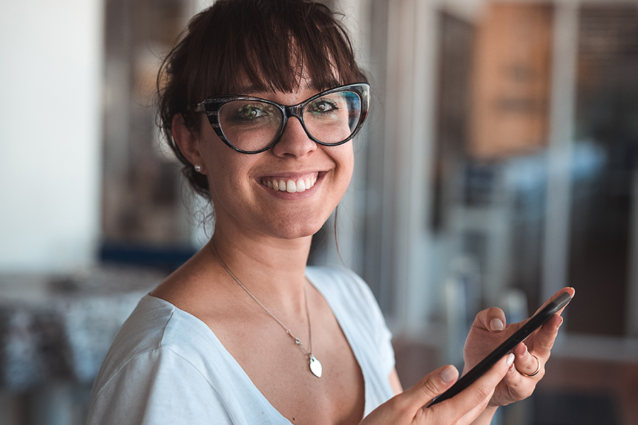 14 Oranges Female User smiling at camera with cell phone in hand