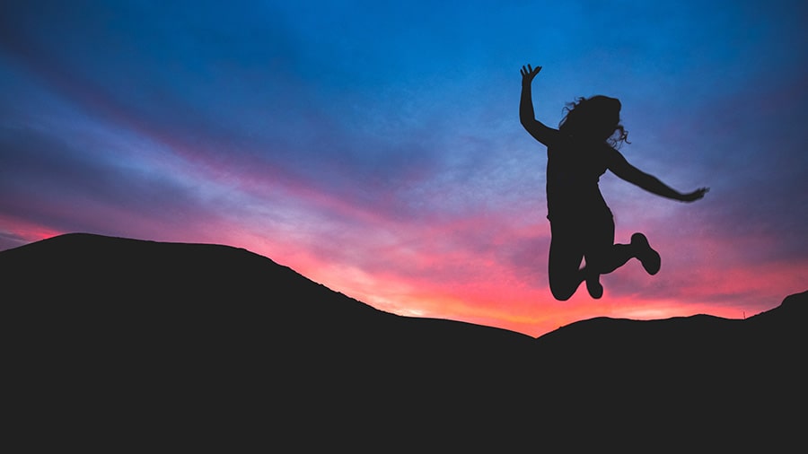 14 Oranges Woman jumping in air at sunrise